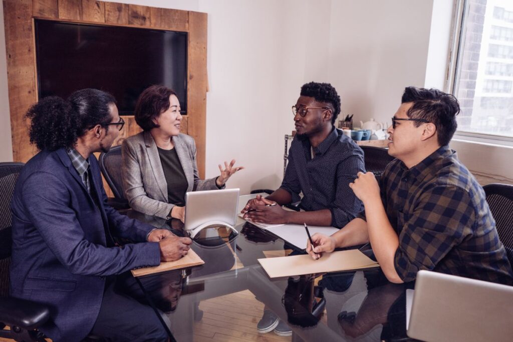 A group of employees sit together in a meeting and chat.