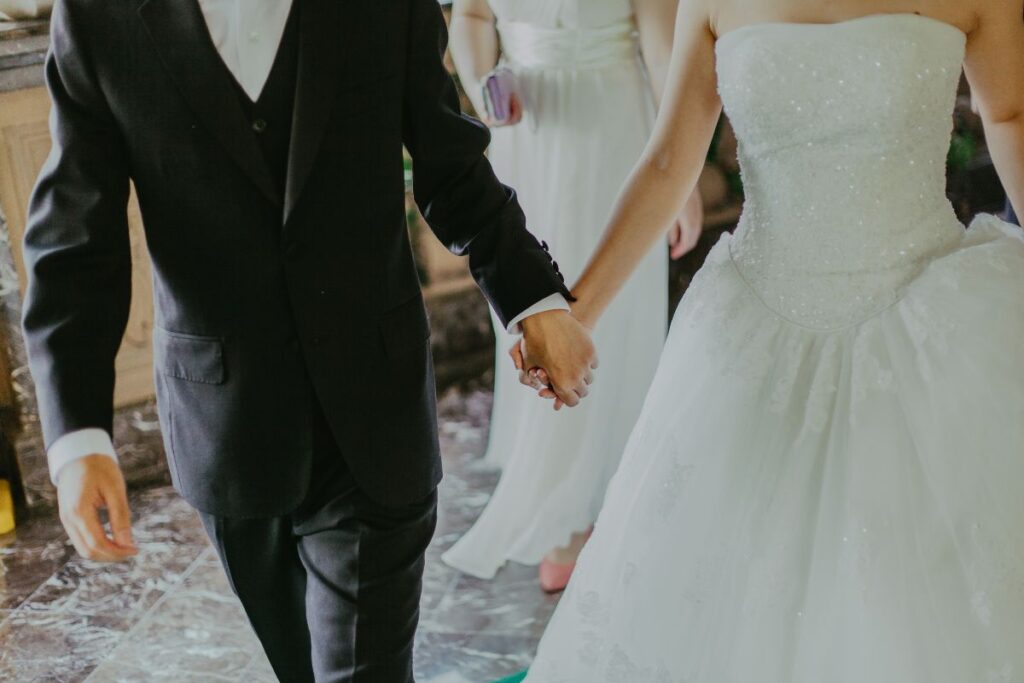 A newly married couple hold hands.