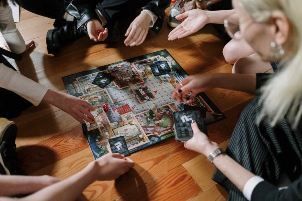 a group of people play a board game on a wooden floor 