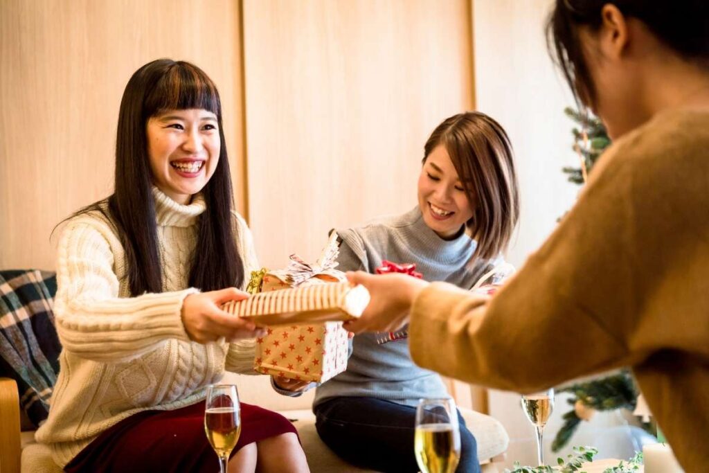 three women smile and share gifts amongst each other 