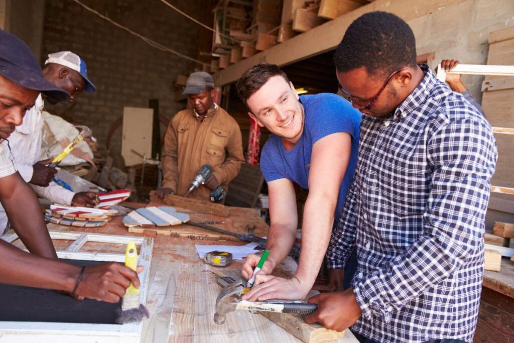 Group of men smiling and working together in construction workshop