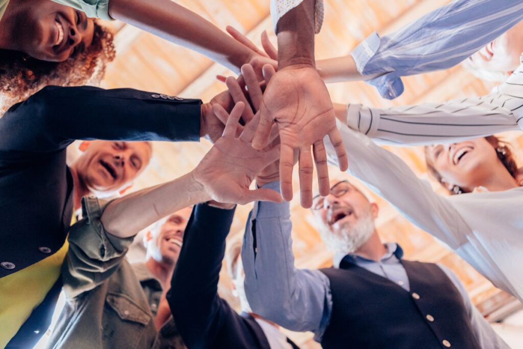 a group of men and women high fiving in the middle of the group