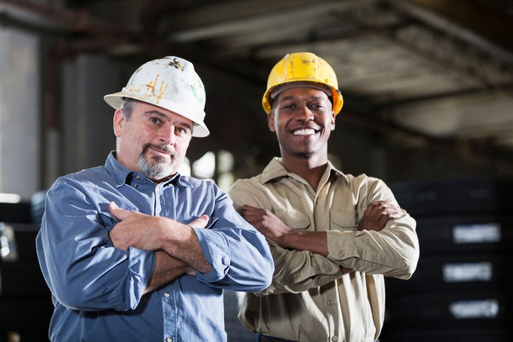 two construction workers stood smiling with their arms crossed 