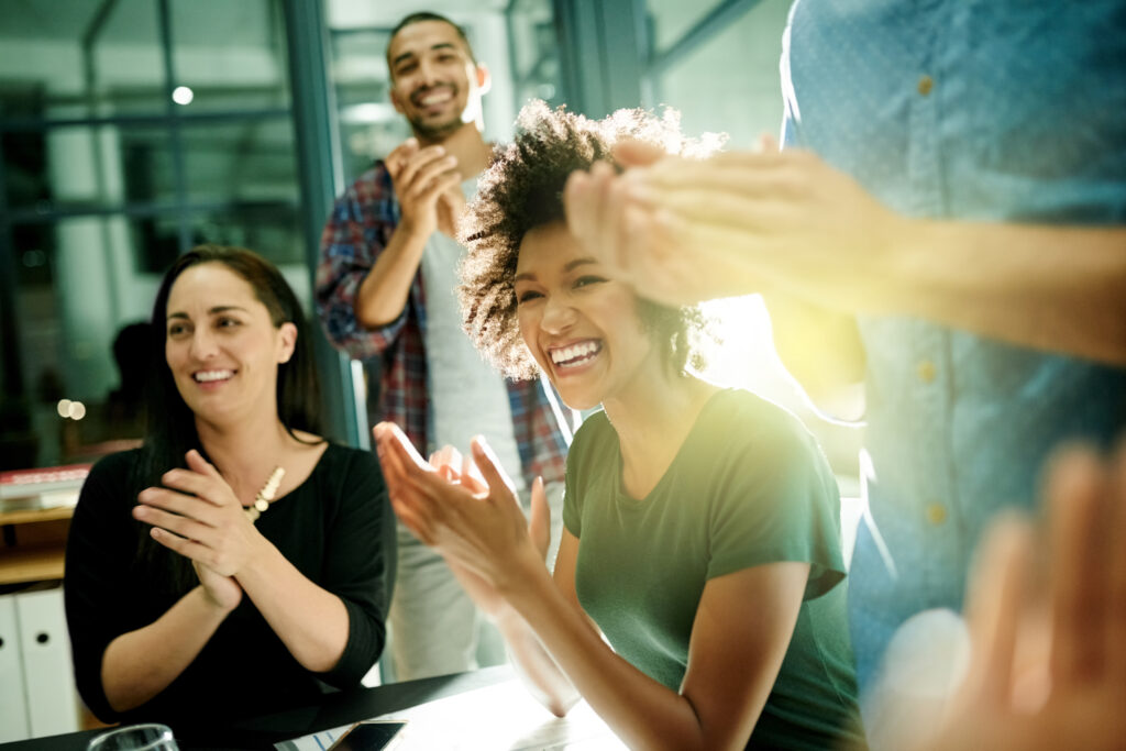 Team of creative business people applauding an achievement whilst working late in their boardroom