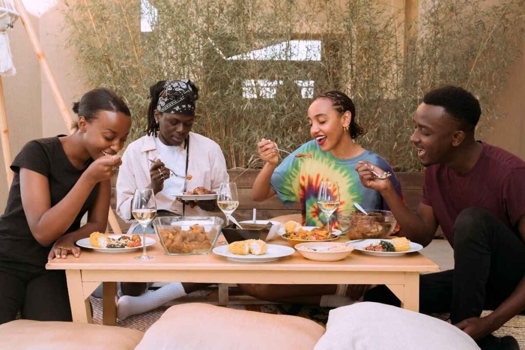 A group of 4 friends share a meal together. They smile and laugh.