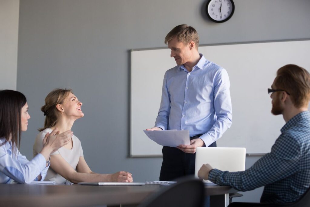 a manager praises the work of one of his team members in a meeting 