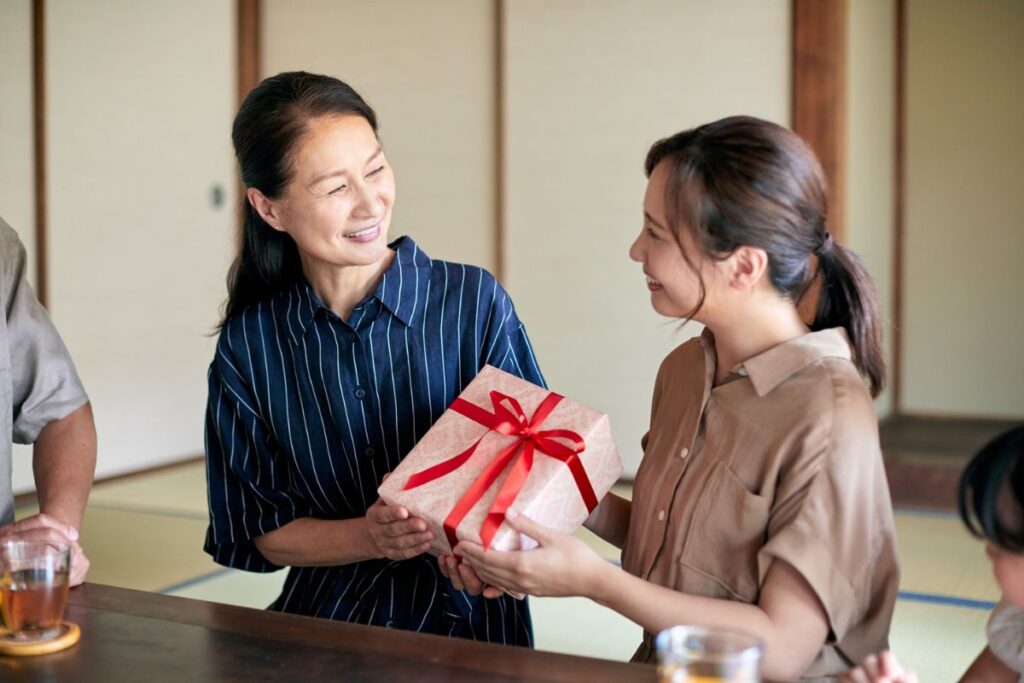 two women exchange a gift between each other. They are both smiling. 