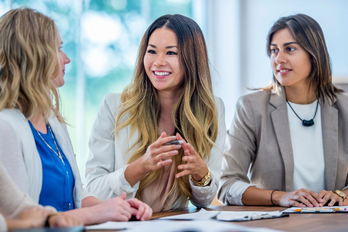 A group of three women colleagues sit together and have a conversation