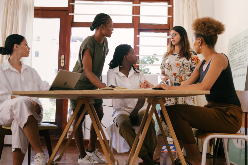 a group of women sit together and discuss work in a meeting 