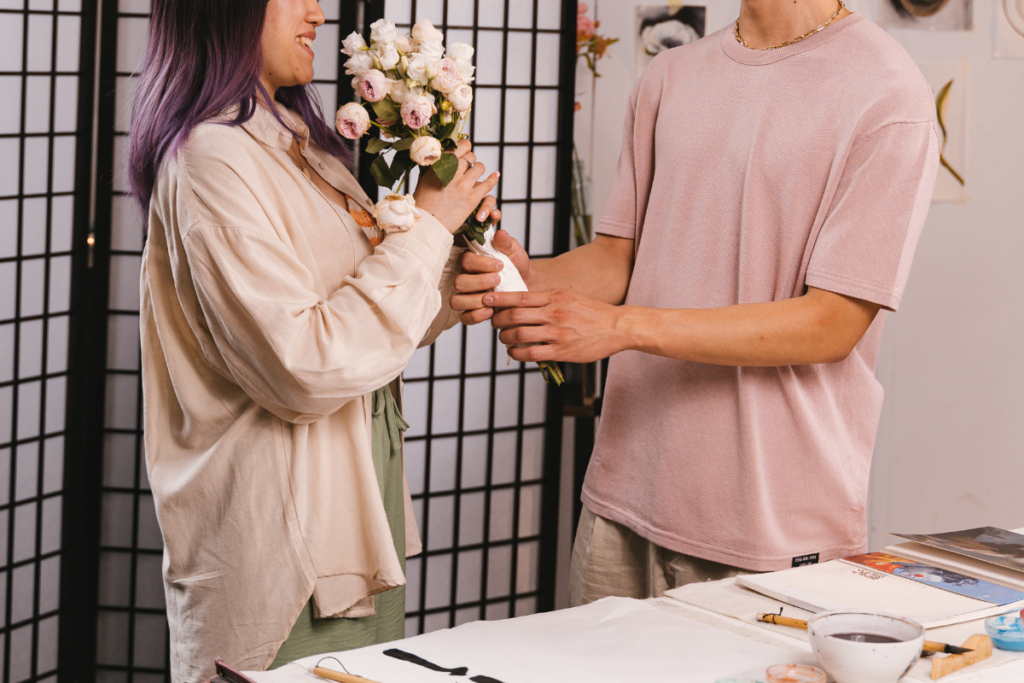 A man hands a woman a bouquet of flowers. She is smiling. 