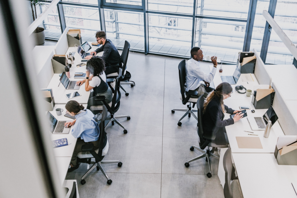 A birds eye view perspective of an office where five employees work at their desks.