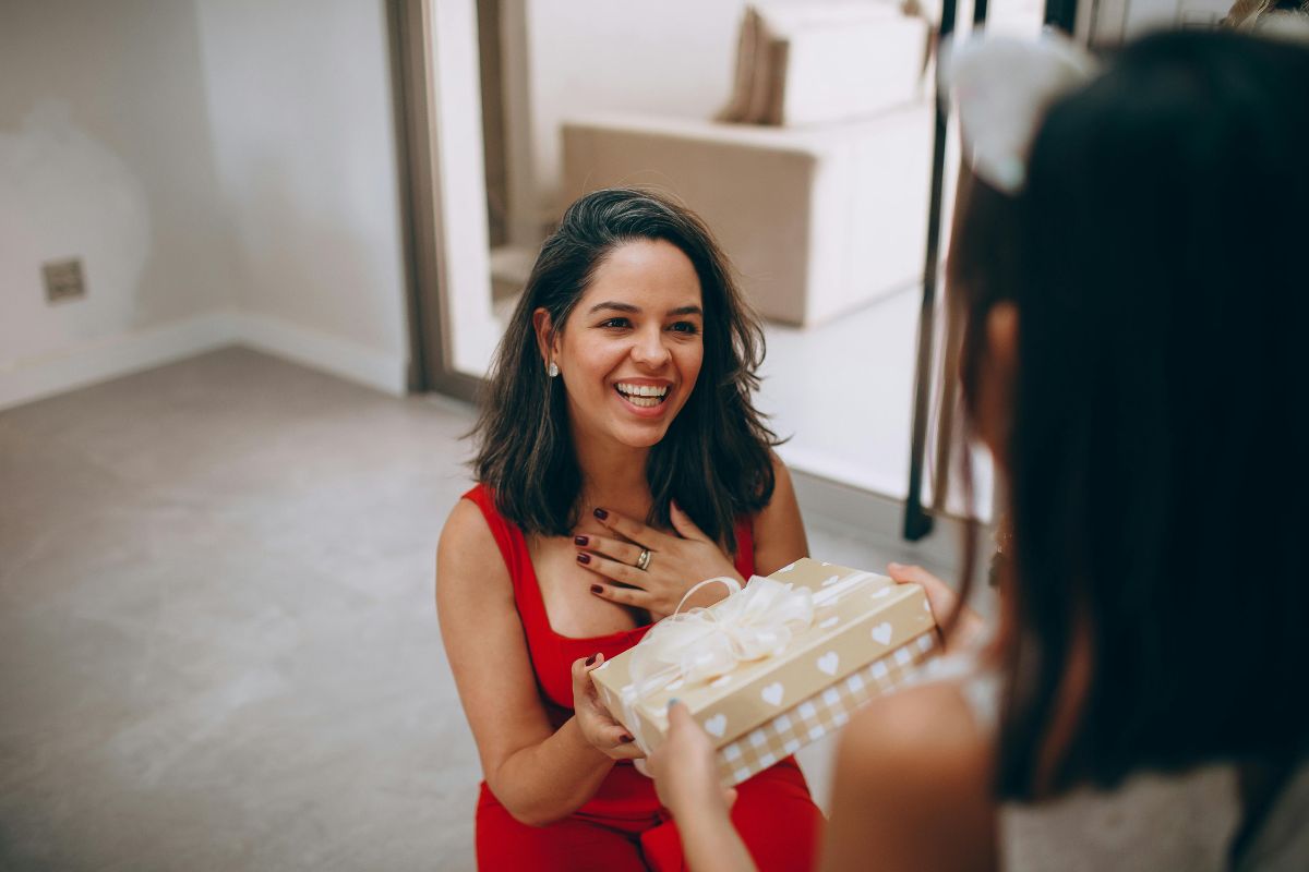 A woman receives a gift and holds her hand to her chest in appreciation