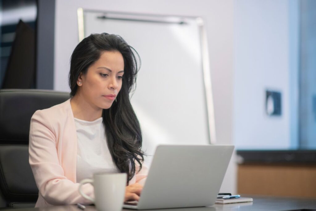 A woman in professional clothes sits and works at her desk.