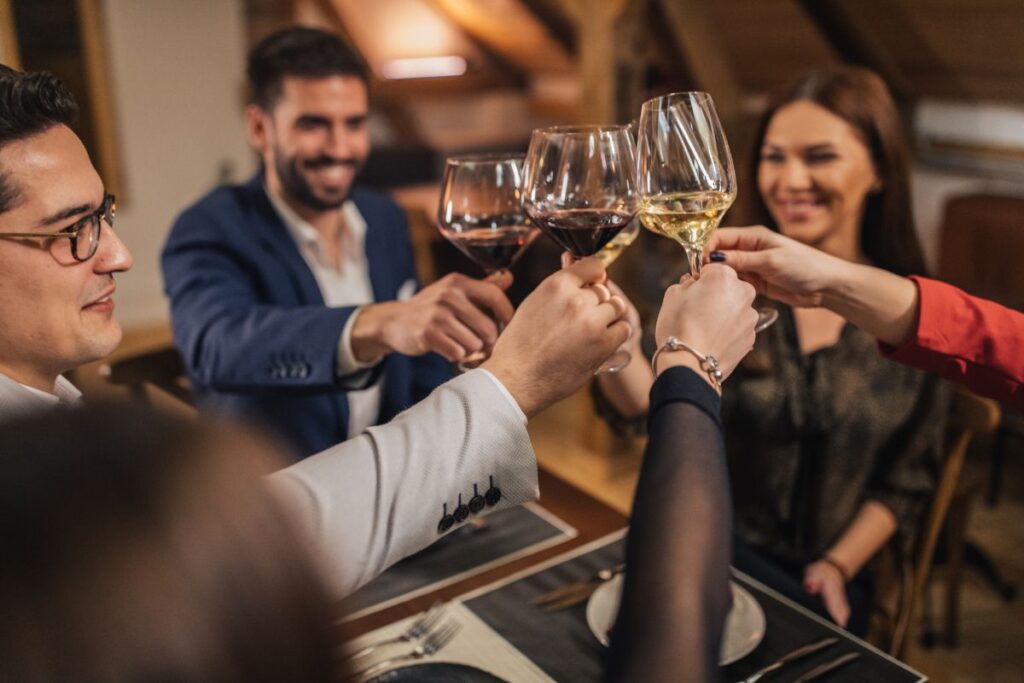 A group of friends hold their wine glasses together, and 'cheers' in celebration. 