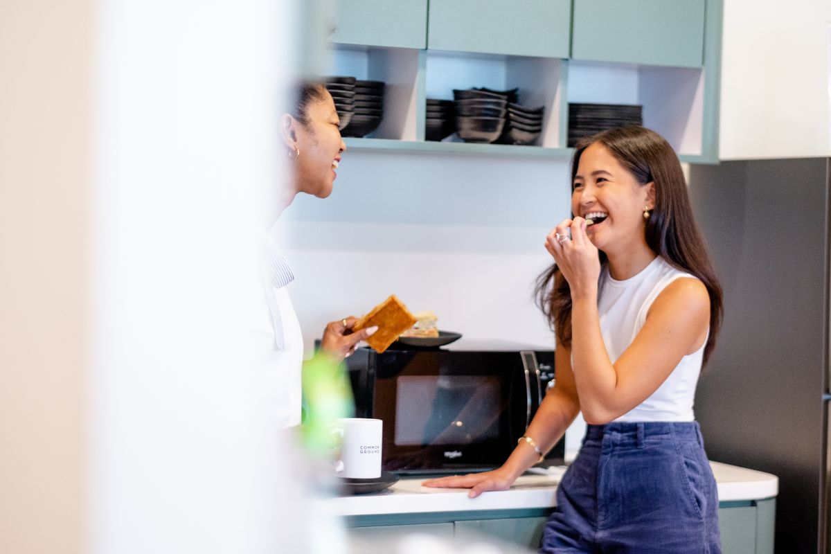 Two co-workers chat together in the work kitchen.