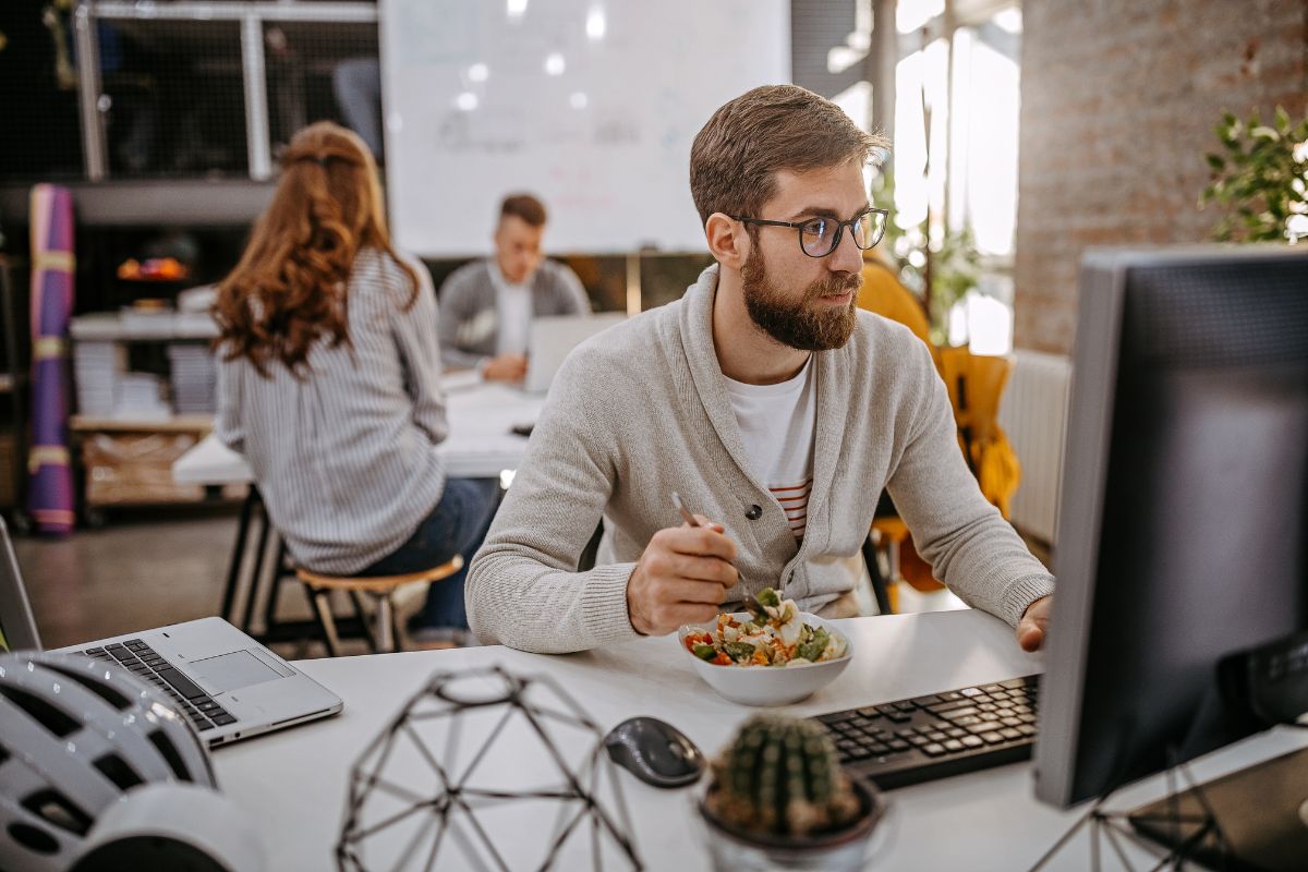 A man sits at his desk and enjoys a gluten free snack.