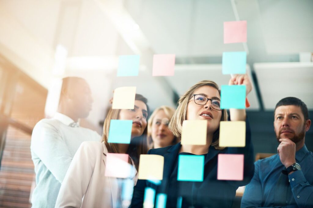 A team work through SMART objectives post-it notes together. The notes are stuck onto a wall.
