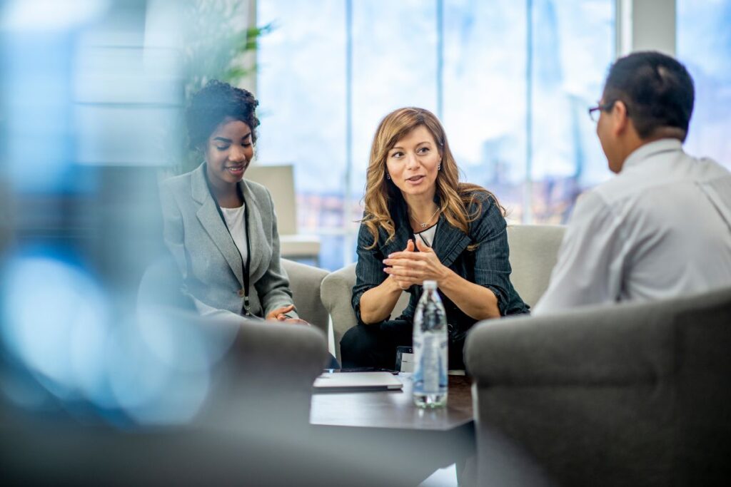 Three employees sit together and work in a meeting.
