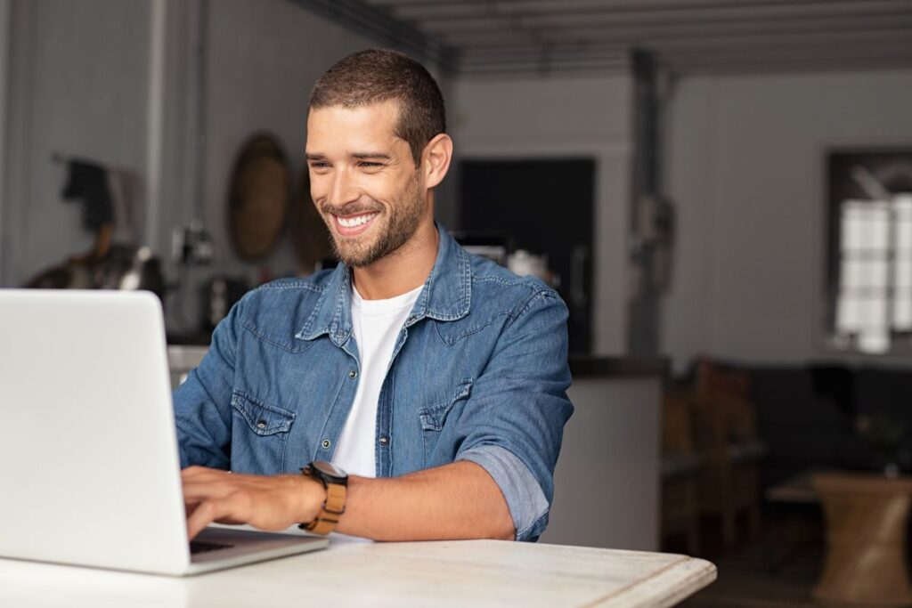 A man smiles at his desk as he receives an e-gift card through his email.