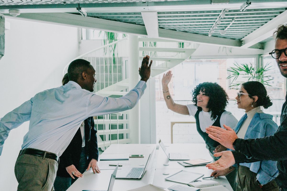 A team of professionals high five over a meeting.