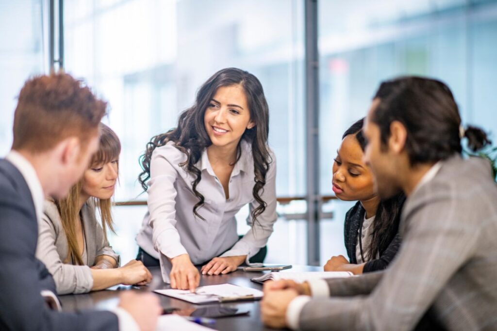 A group of professionals sit in a sales meeting and collaborate.