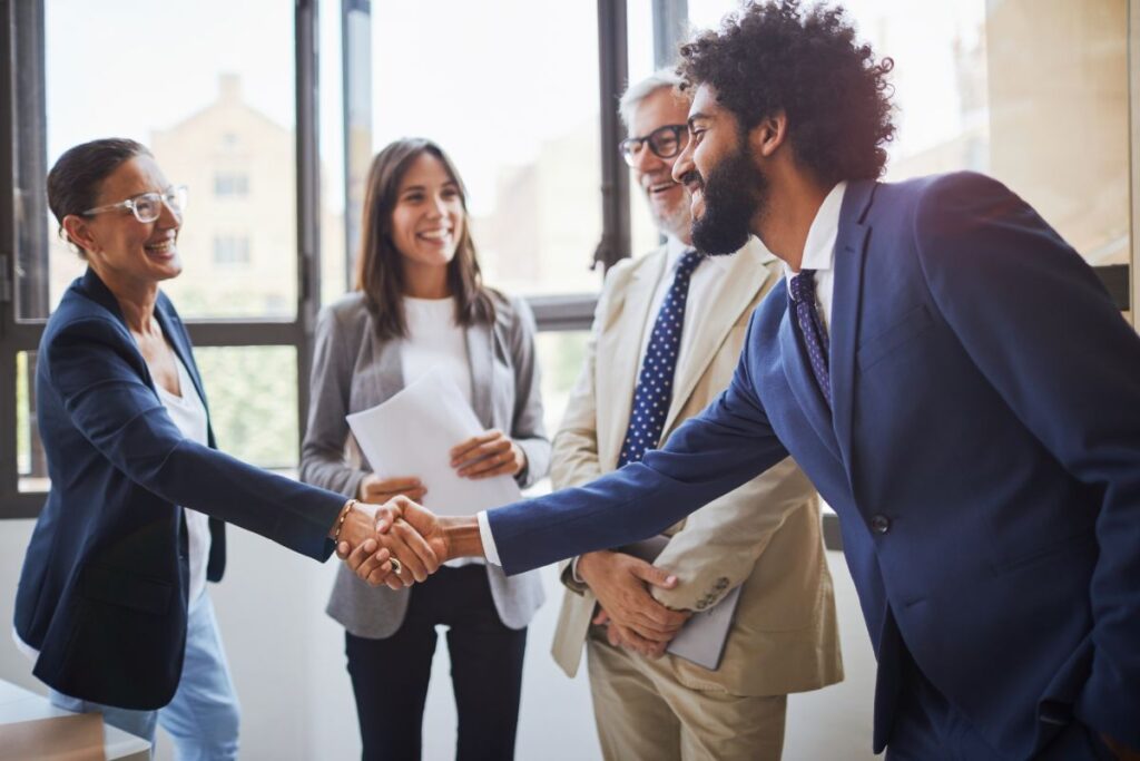 Two professionals shake hands in a meeting in celebration.