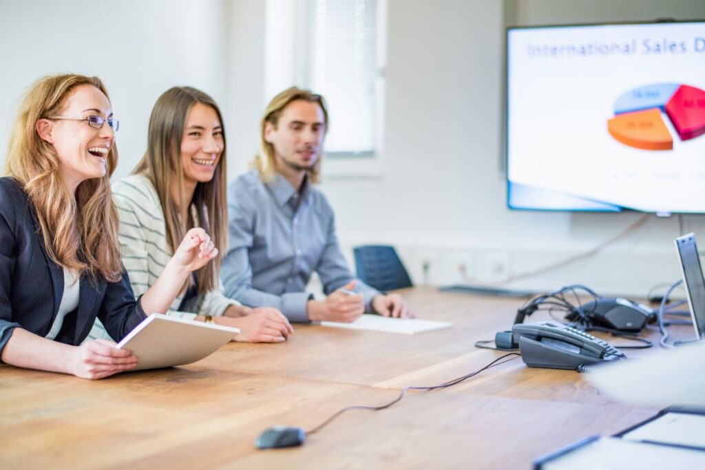 A group of sales professionals sit in a meeting room and collaborate.