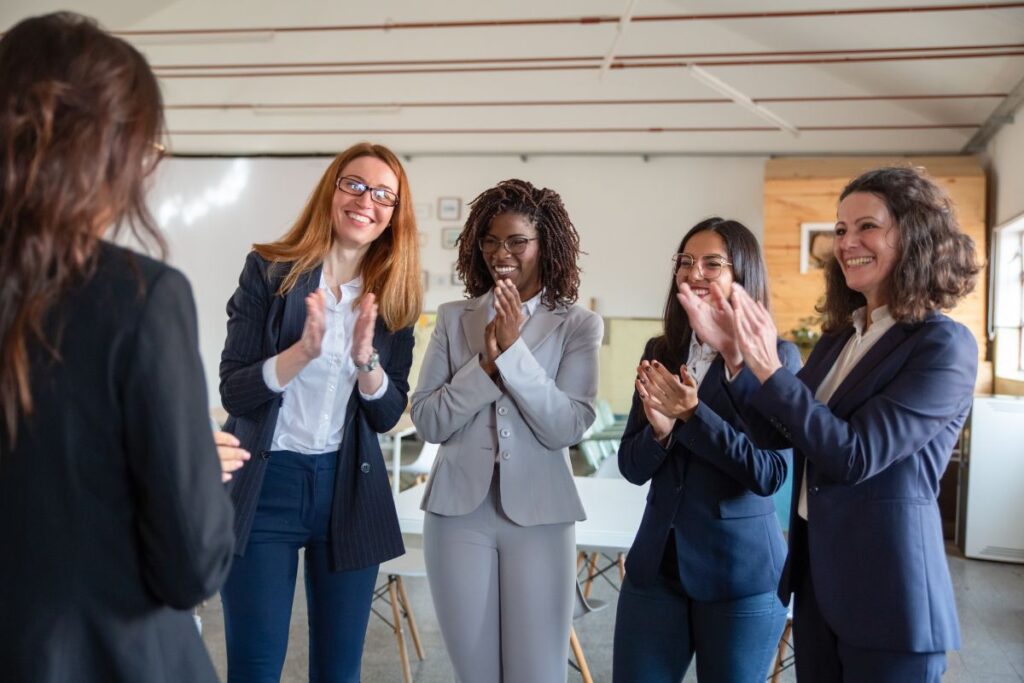 Employees stand in a group together and do a round of applause