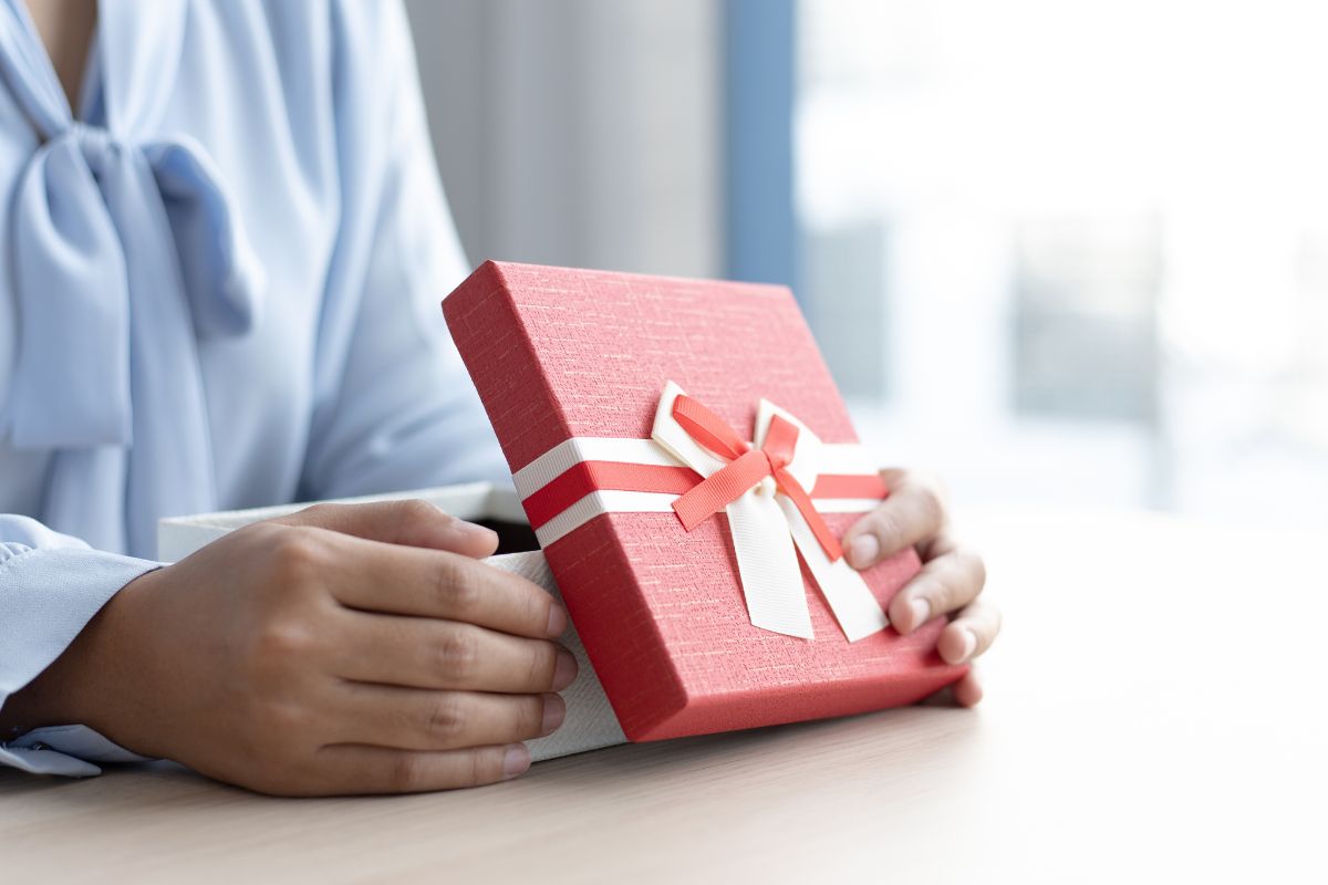 Someone opens their corporate Christmas gift at their desk
