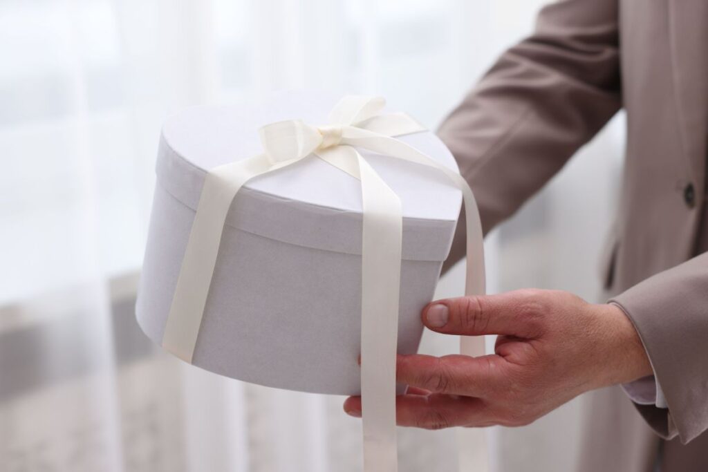 A man holding a white heart-shaped giftbox as a wedding present