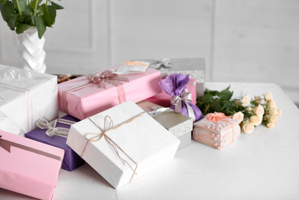 A white wedding table piled with gifts and white flowers