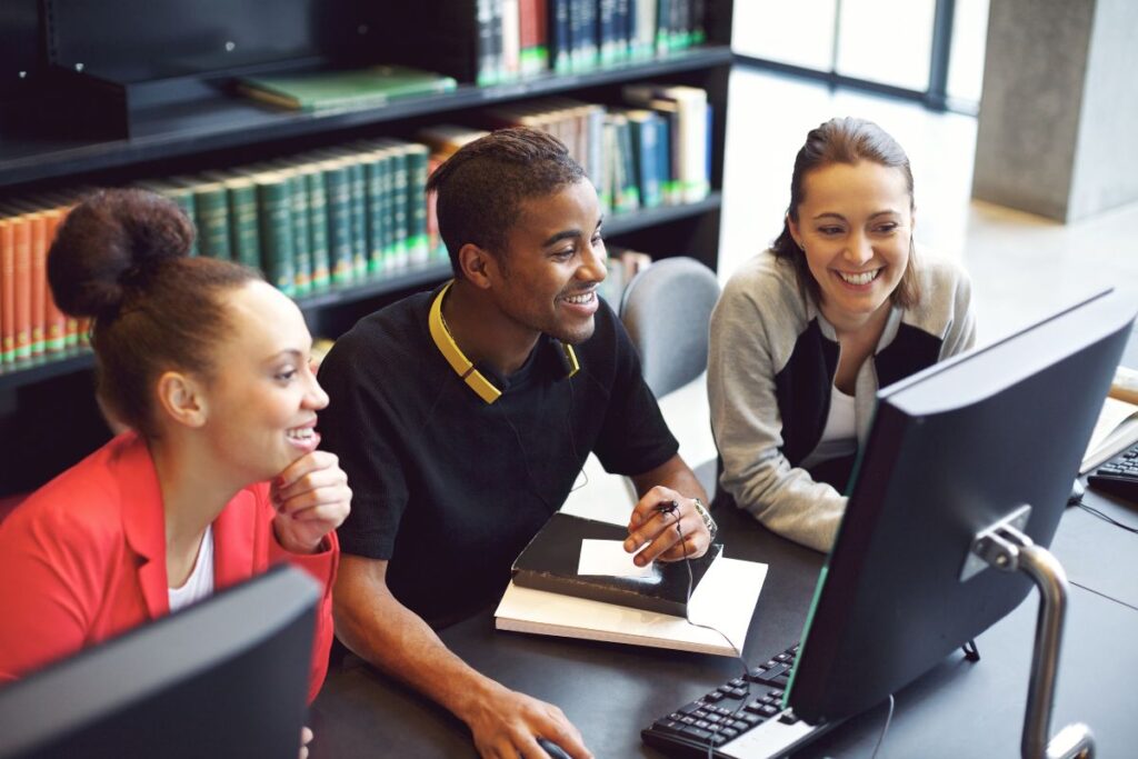 A team of three smile as they work together on a project