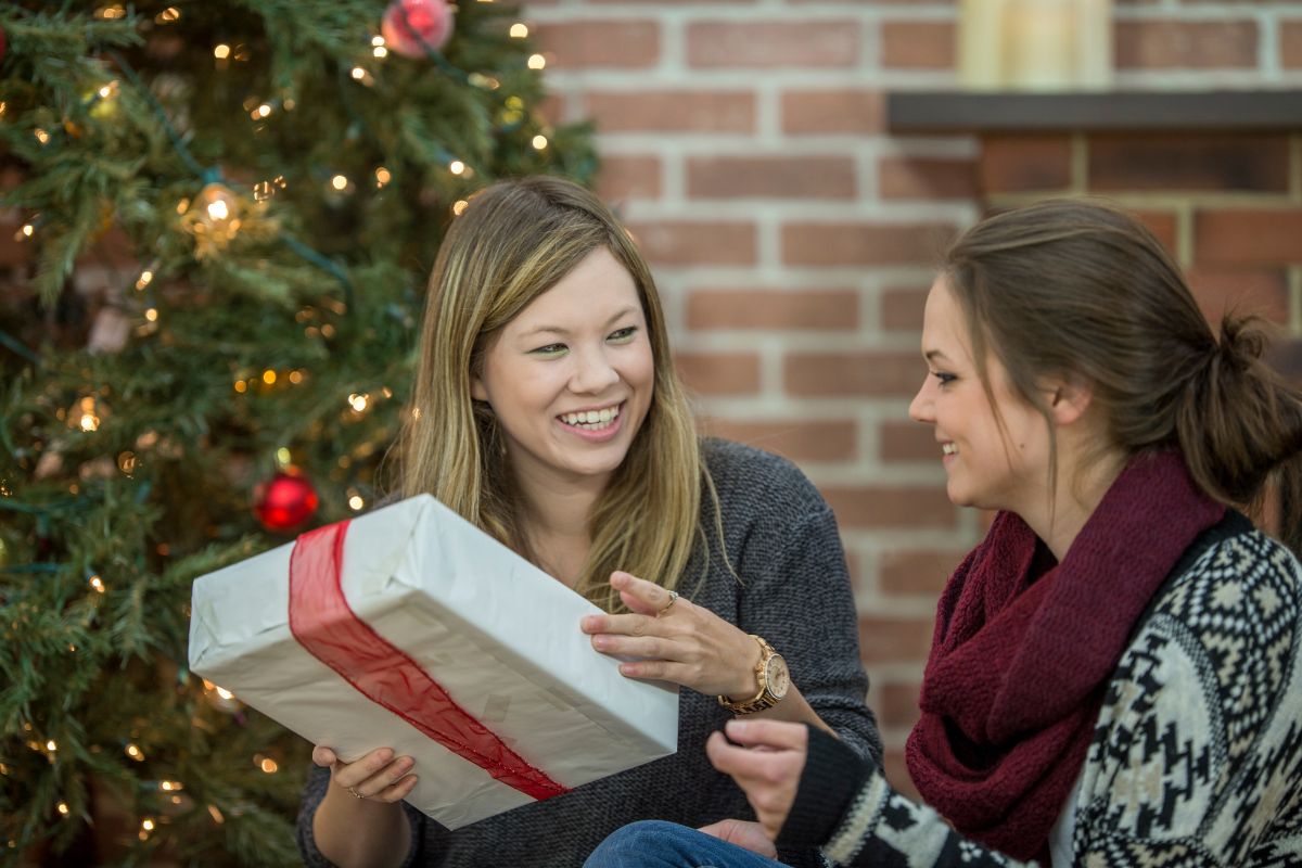 Two co-workers exchange gifts under a Christmas tree