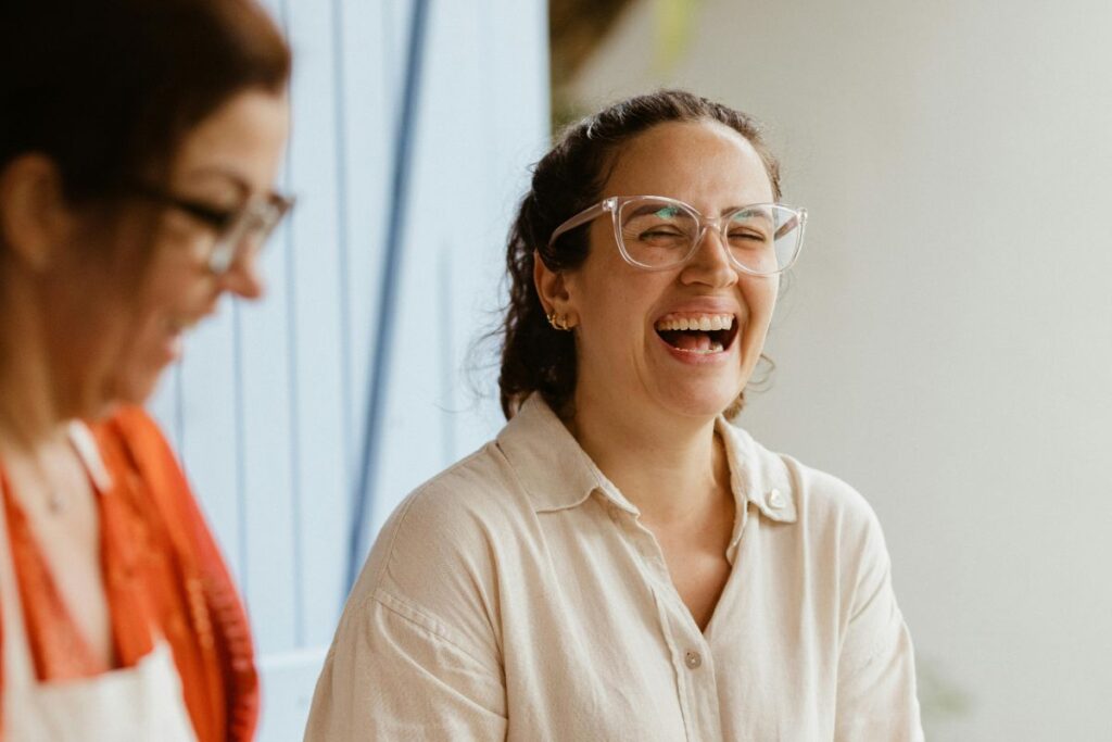 A female employee laughs with a co-worker. She is wearing glasses.