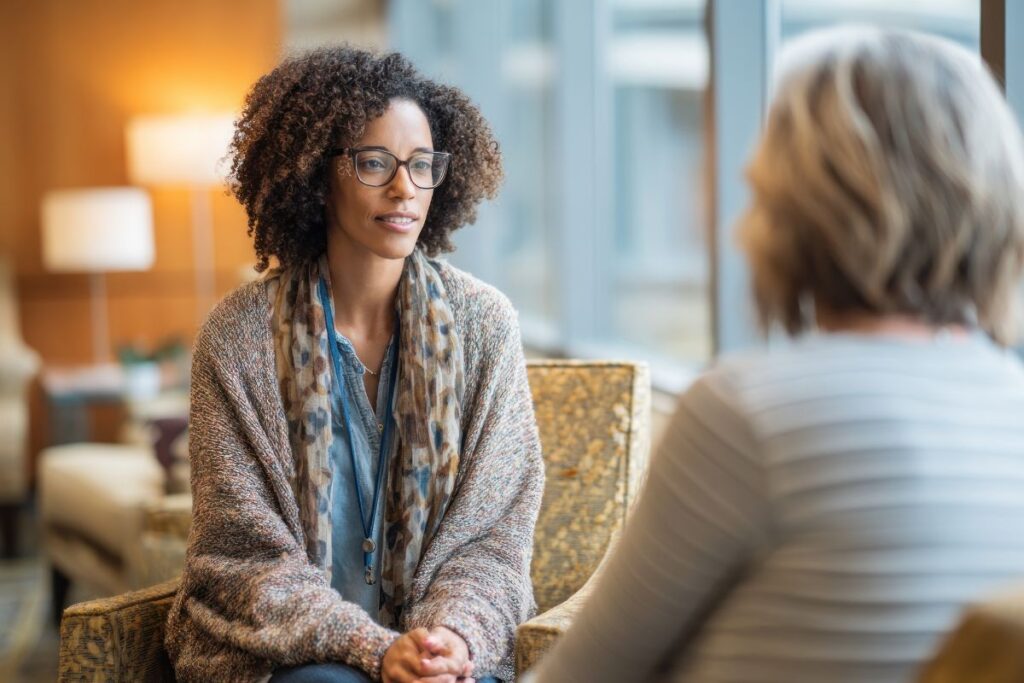 Two women sit across from each other and discuss an end of year review meeting.