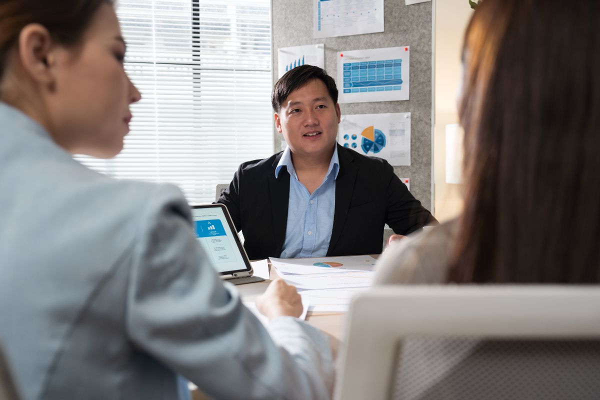 A man sits opposite two women in a corporate meeting