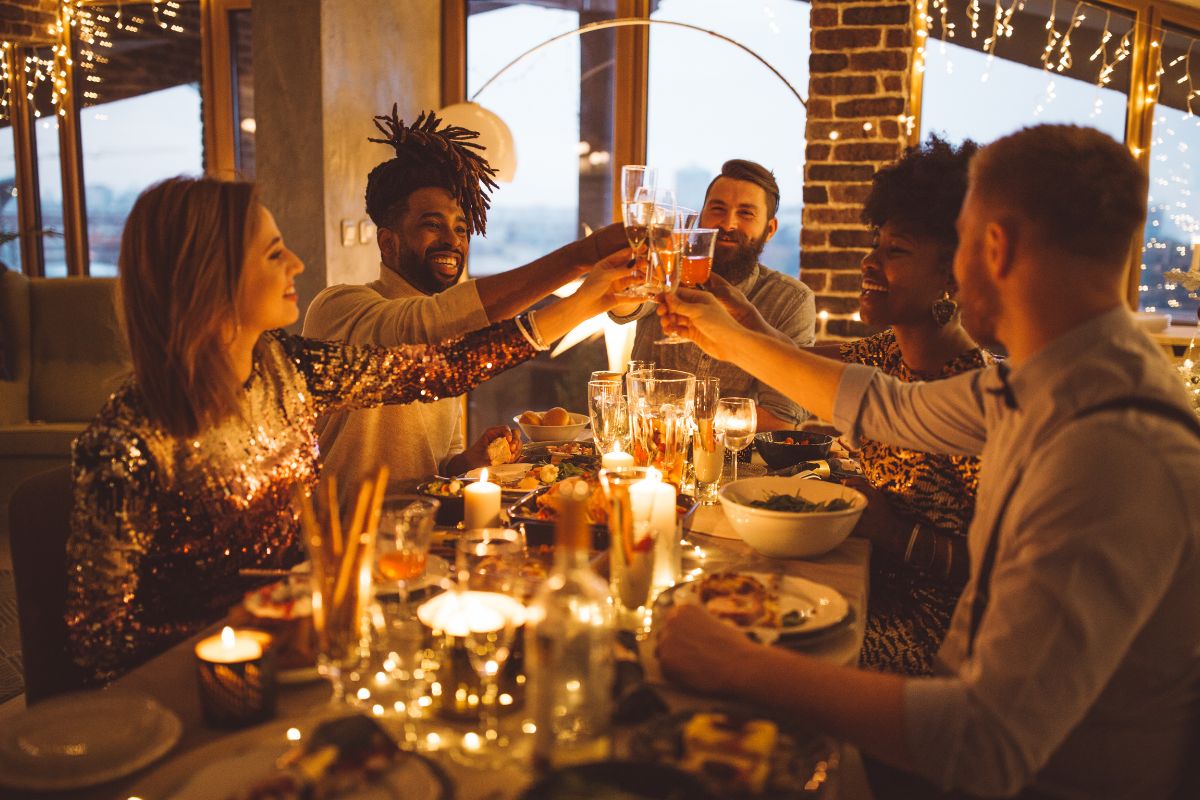 A group of employees gather at a dining table and eat together. They cheers in the middle of the table