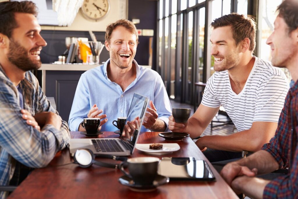 A group of men laugh together while in a meeting