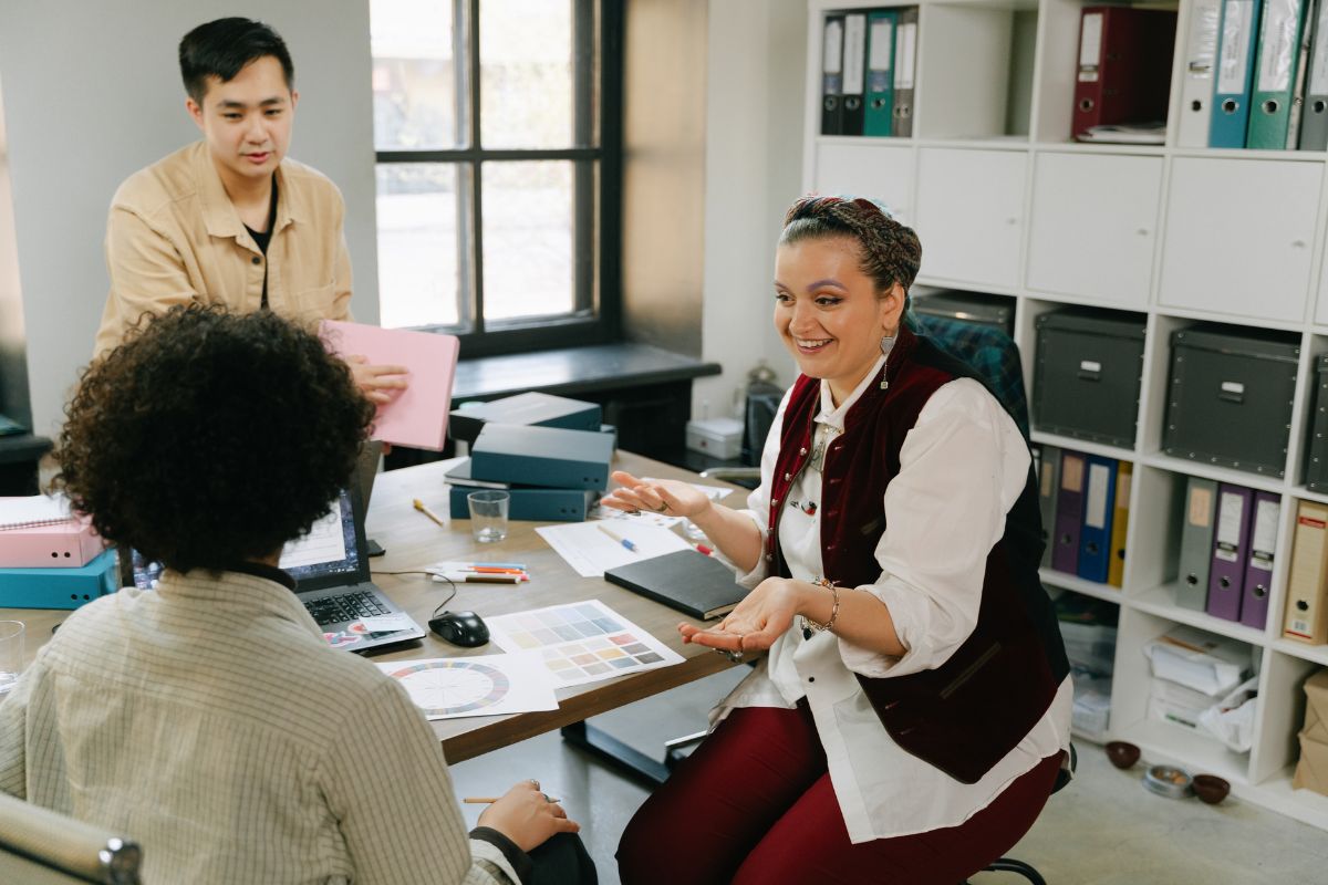 A group of three employees have a meeting together to discuss employee experience strategy