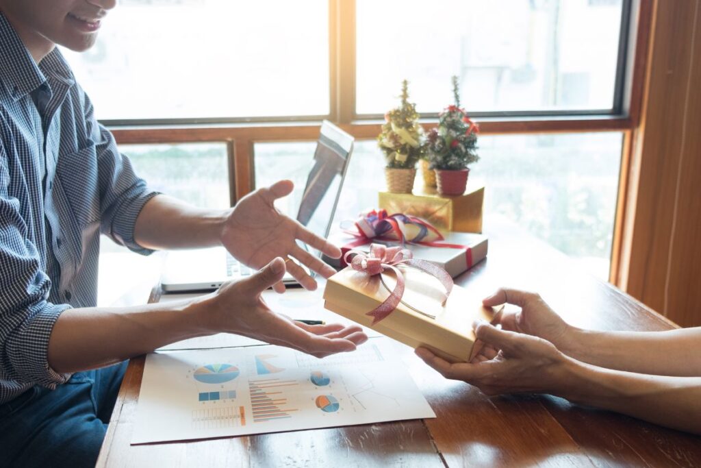 Two colleagues exchange corporate gifts